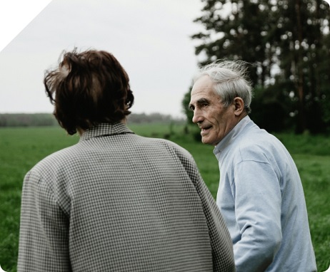 Elderly man walks alongside a younger man in an open field. 